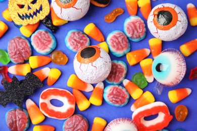 Photo of Delicious bright candies on blue background, flat lay. Halloween sweets