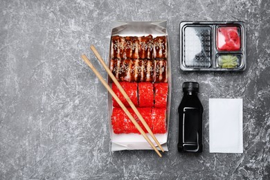 Delicious sushi rolls served on grey textured table, flat lay. Food delivery