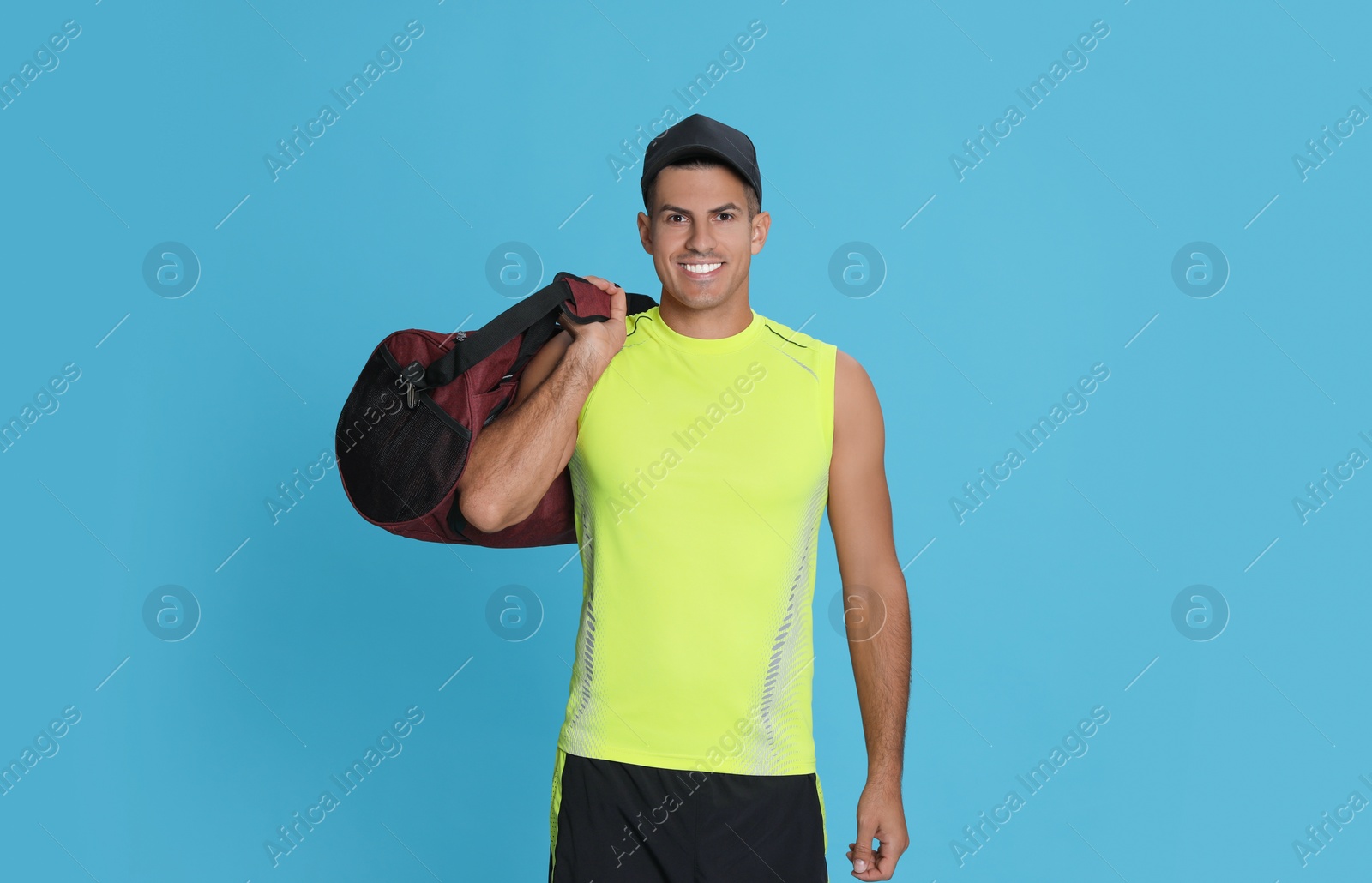 Photo of Handsome man with sports bag on light blue background