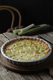 Tasty leek pie and raw stems on old wooden table