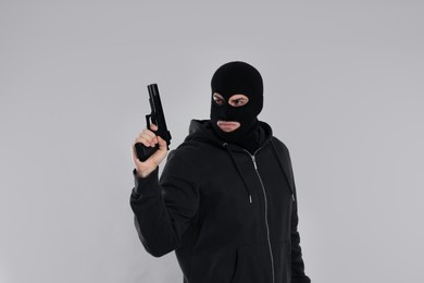 Photo of Man wearing black balaclava with gun on light grey background
