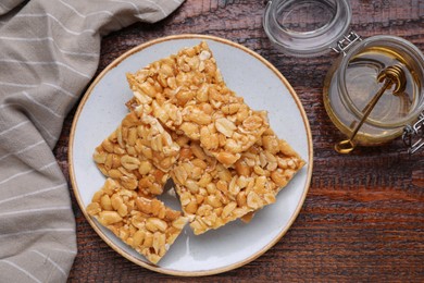 Photo of Delicious peanut bars (kozinaki) and ingredients on wooden table, flat lay