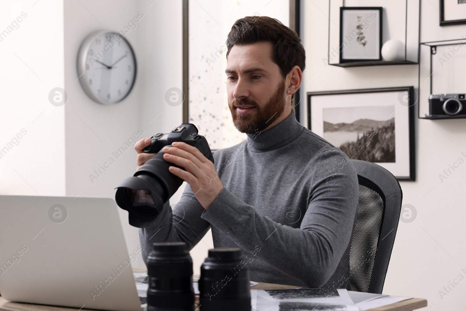 Photo of Professional photographer with digital camera at table in office