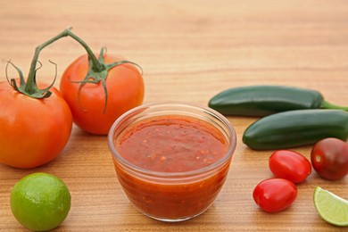 Photo of Tasty salsa sauce and different ingredients on wooden table