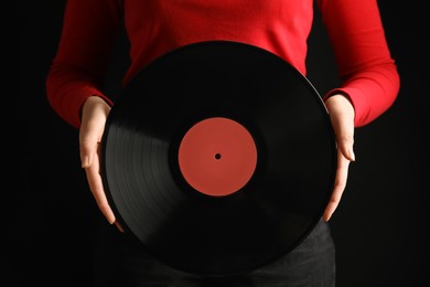 Woman with vintage vinyl record on black background, closeup