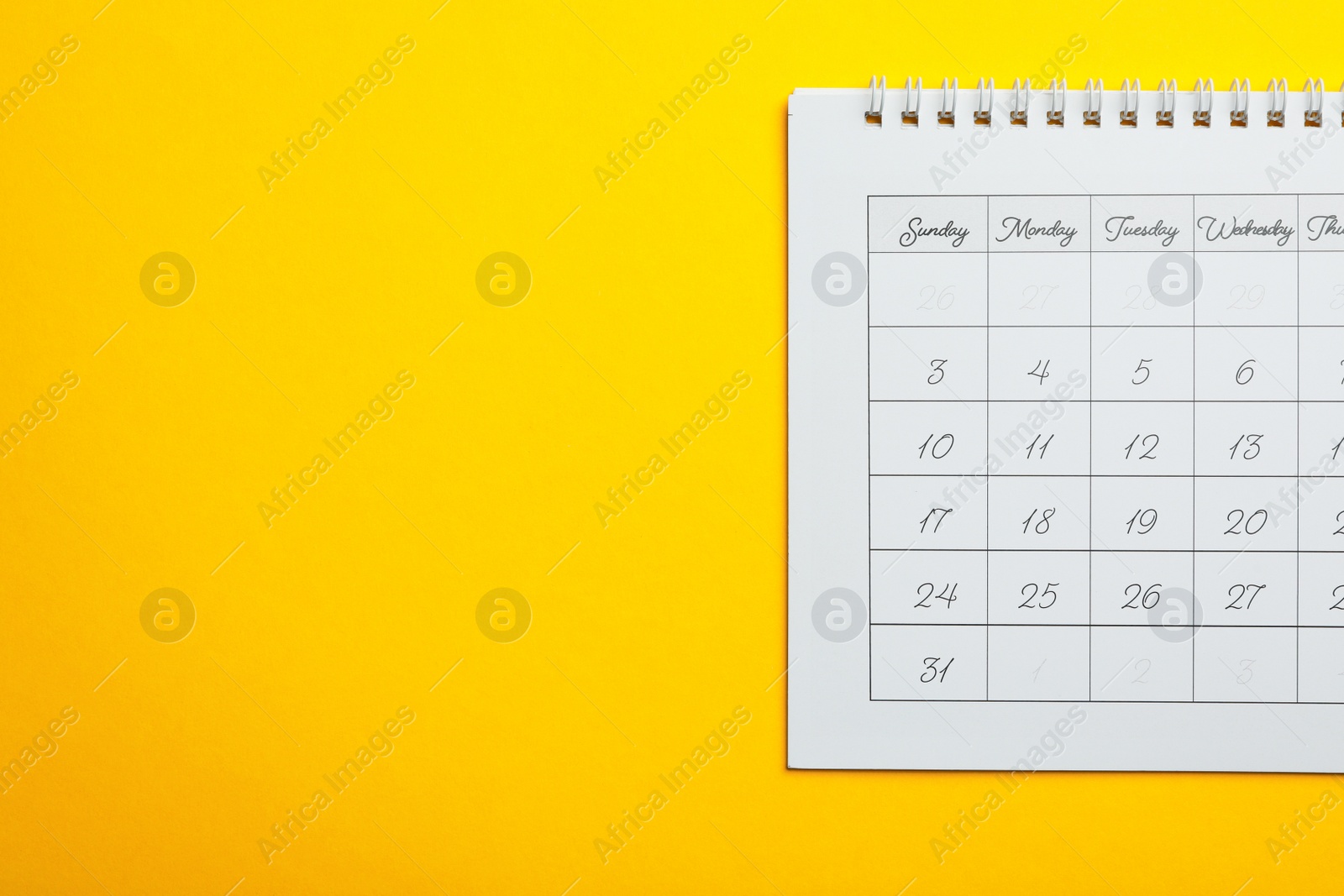 Photo of Paper calendar on yellow background, top view. Space for text