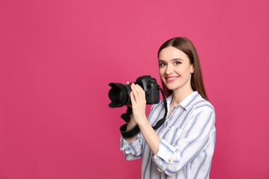 Professional photographer with modern camera on pink background