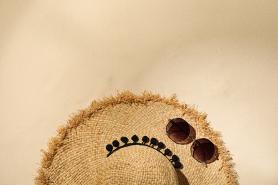 Flat lay composition with hat and sunglasses on sand, space for text. Beach objects