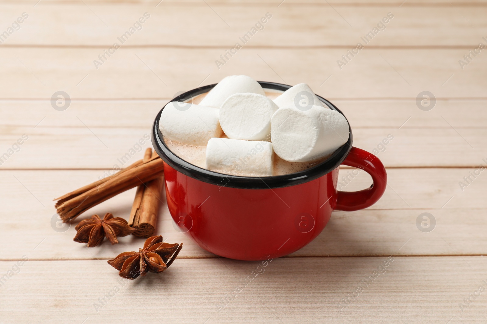 Photo of Tasty hot chocolate with marshmallows and spices on light wooden table, closeup