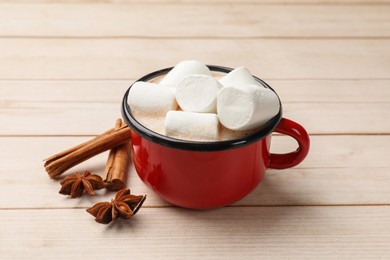 Photo of Tasty hot chocolate with marshmallows and spices on light wooden table, closeup