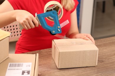 Photo of Post office worker packing parcel at counter indoors, closeup