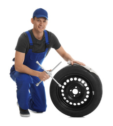 Portrait of professional auto mechanic with wheel and lug wrench on white background