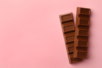 Delicious chocolate bars on pink background, flat lay. Space for text