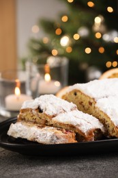 Photo of Traditional Christmas Stollen with icing sugar on grey table, closeup