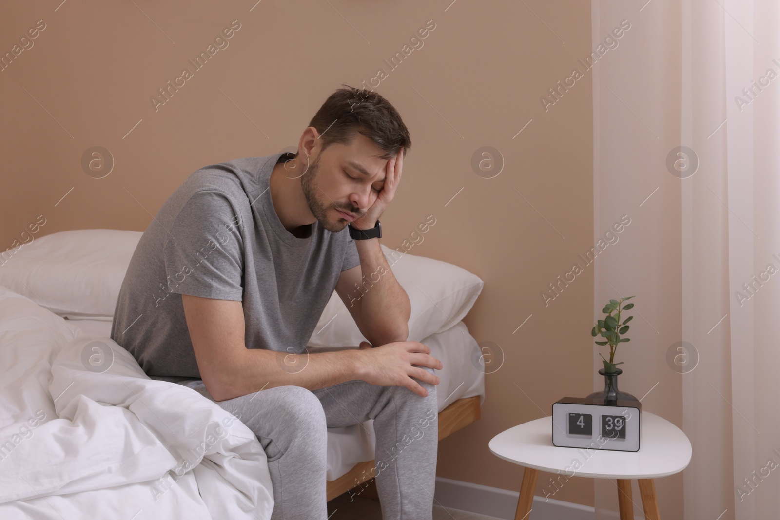Photo of Sleepy man sitting on bed at home