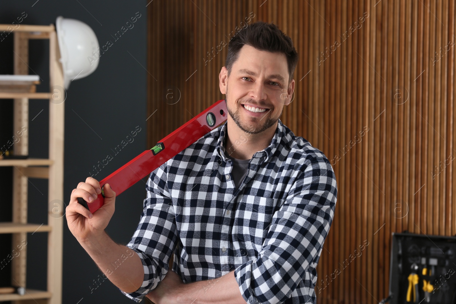 Photo of Handsome working man with building level indoors. Home repair