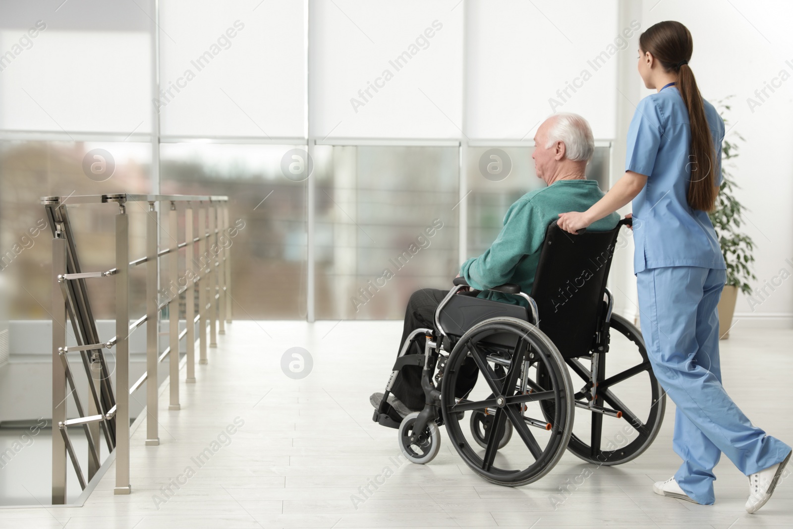 Photo of Nurse assisting senior man in wheelchair at hospital