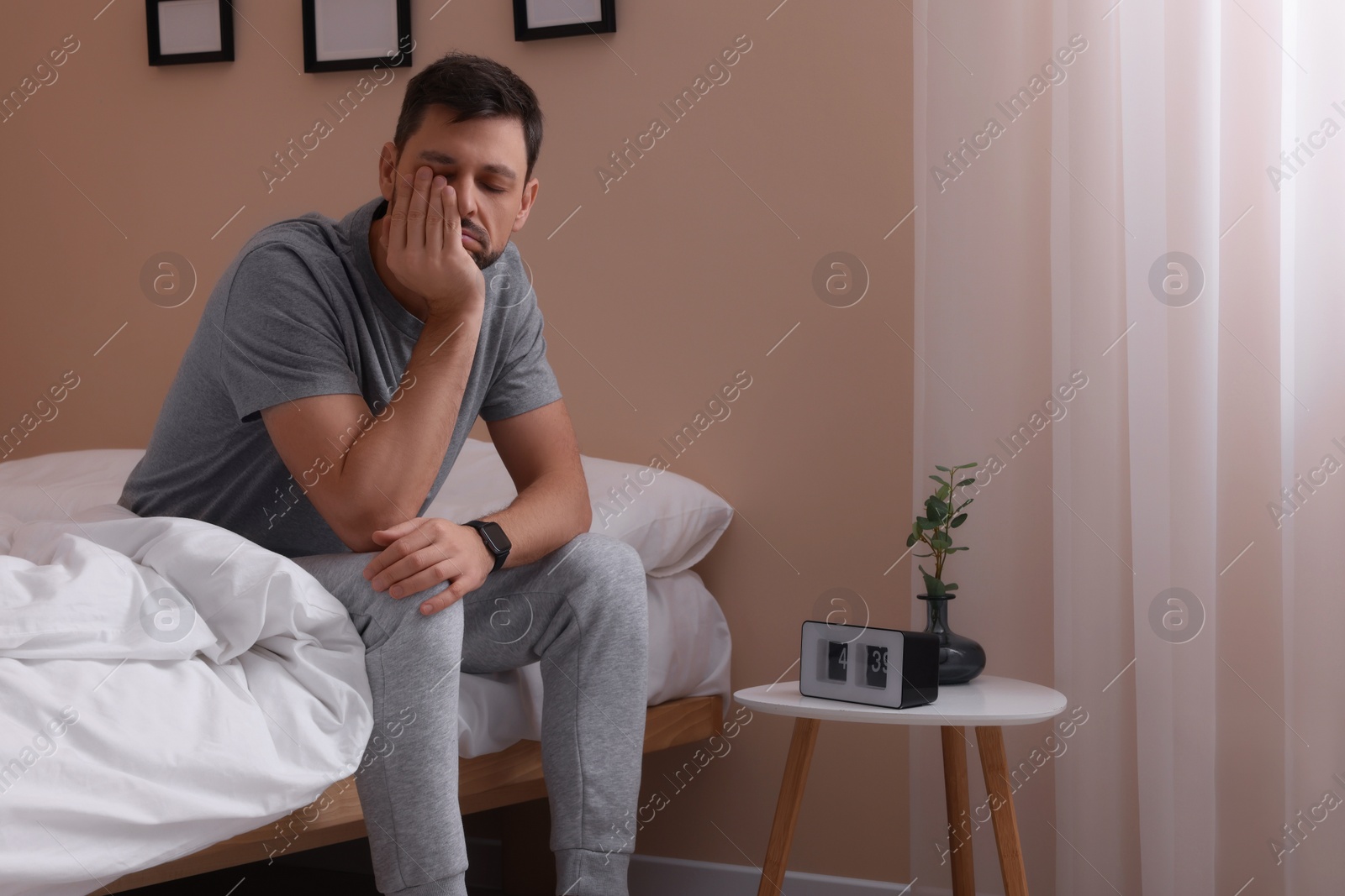 Photo of Sleepy man sitting on bed at home