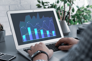 Image of  Broker working with laptop at table, closeup. Forex trading