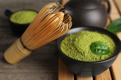 Green matcha powder and bamboo whisk on wooden table, closeup