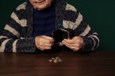 Poor senior woman with empty wallet and coins at table, closeup