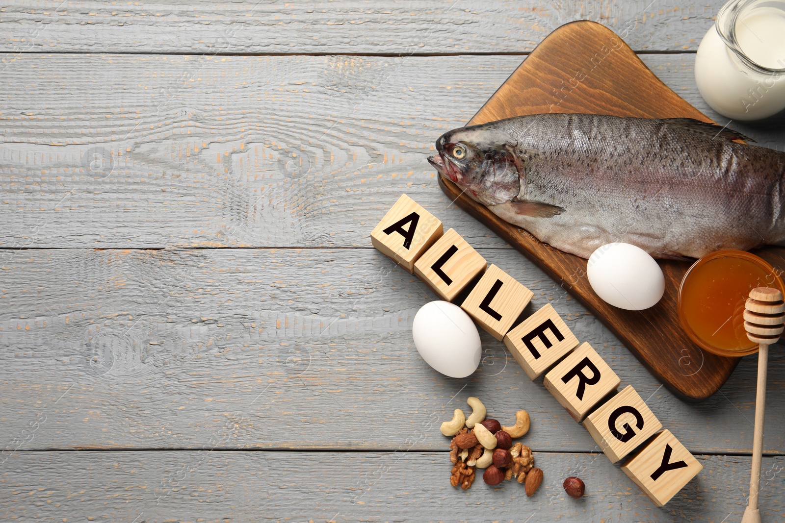 Image of Food allergy. Different fresh products and cubes on grey wooden table, flat lay with space for text