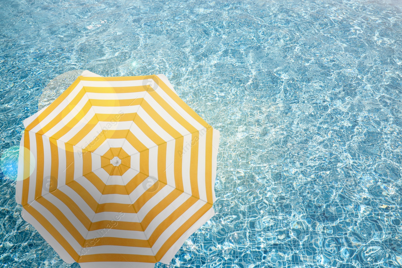 Image of Open beach umbrella and swimming pool. Summer vacation