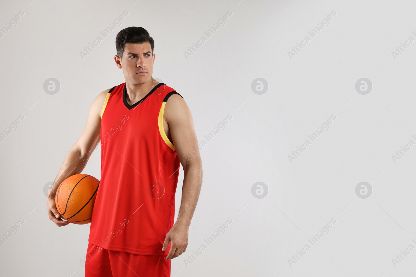 Photo of Basketball player with ball on grey background. Space for text