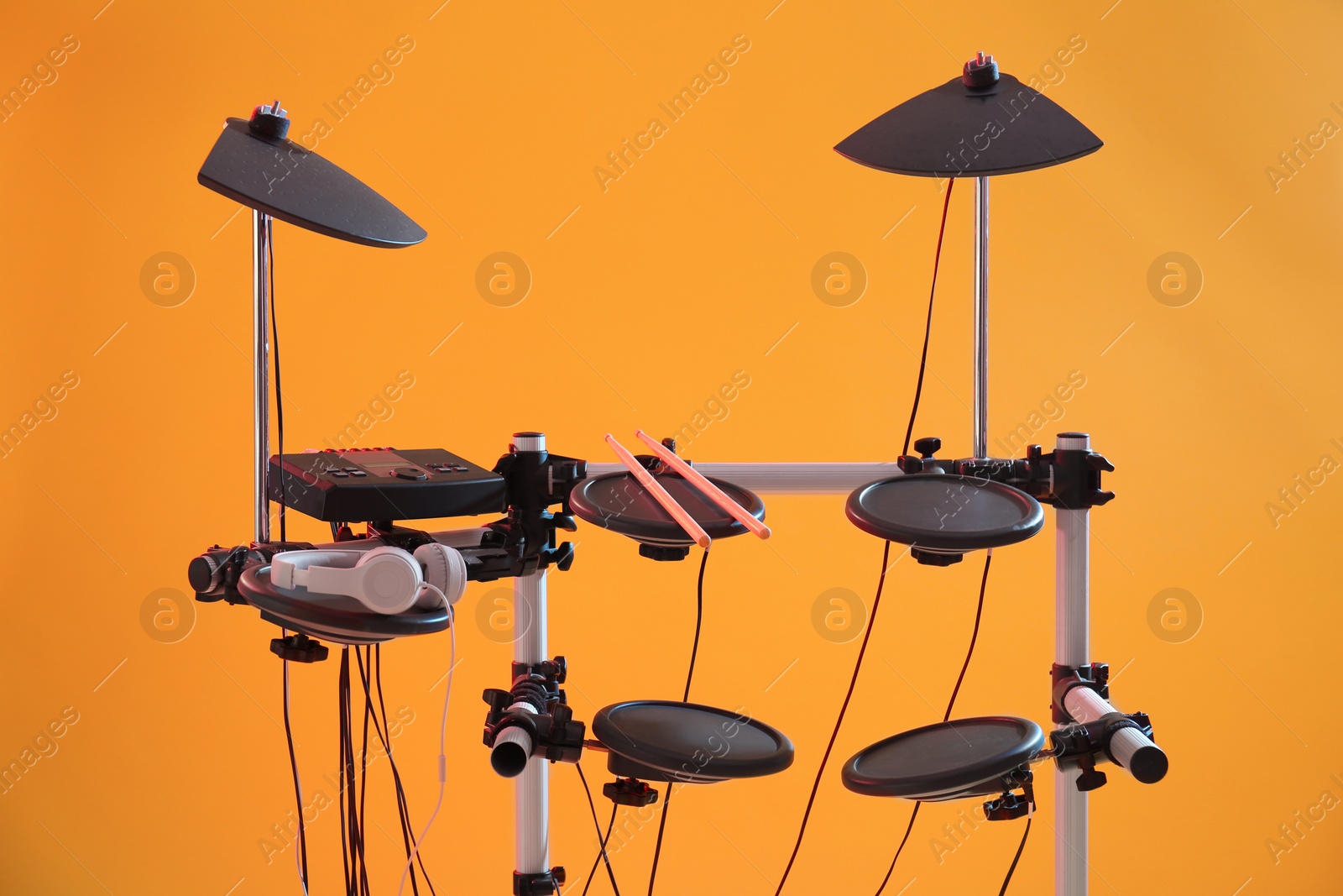 Photo of Modern electronic drum kit on orange background. Musical instrument