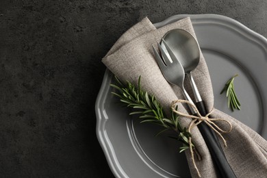 Stylish setting with cutlery and napkin on black table, top view. Space for text