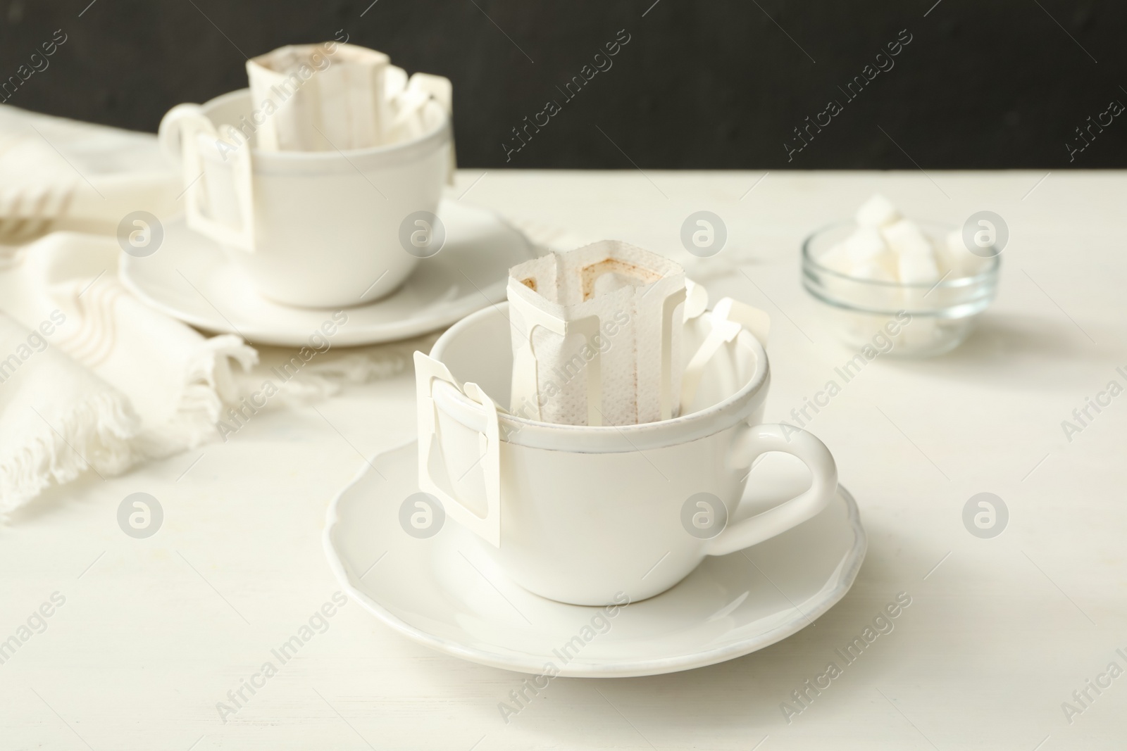 Photo of Cup with drip coffee bag on white wooden table