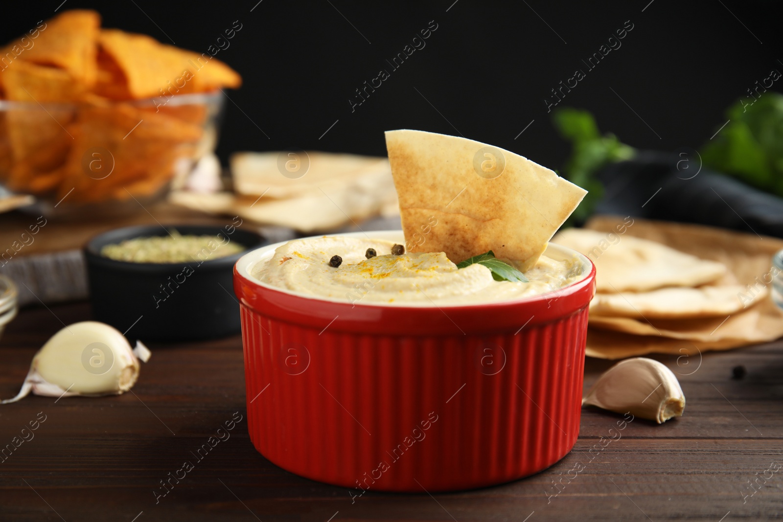 Photo of Delicious hummus with pita chips on wooden table, closeup