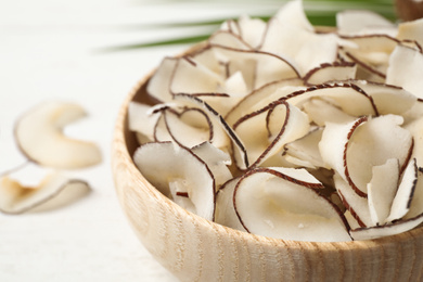 Photo of Tasty coconut chips in wooden bowl, closeup