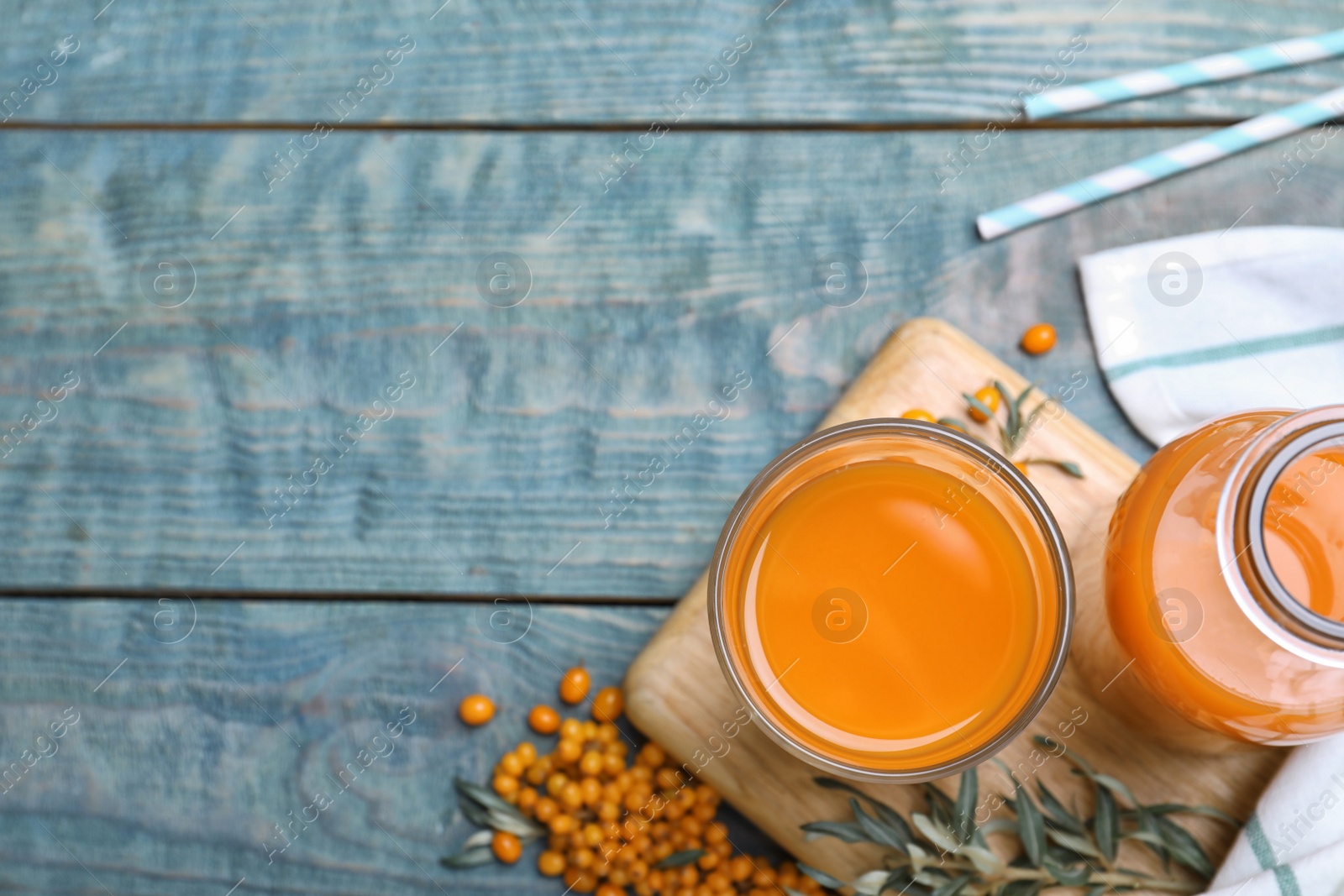 Photo of Delicious sea buckthorn juice on light blue wooden table, top view. Space for text