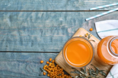 Delicious sea buckthorn juice on light blue wooden table, top view. Space for text