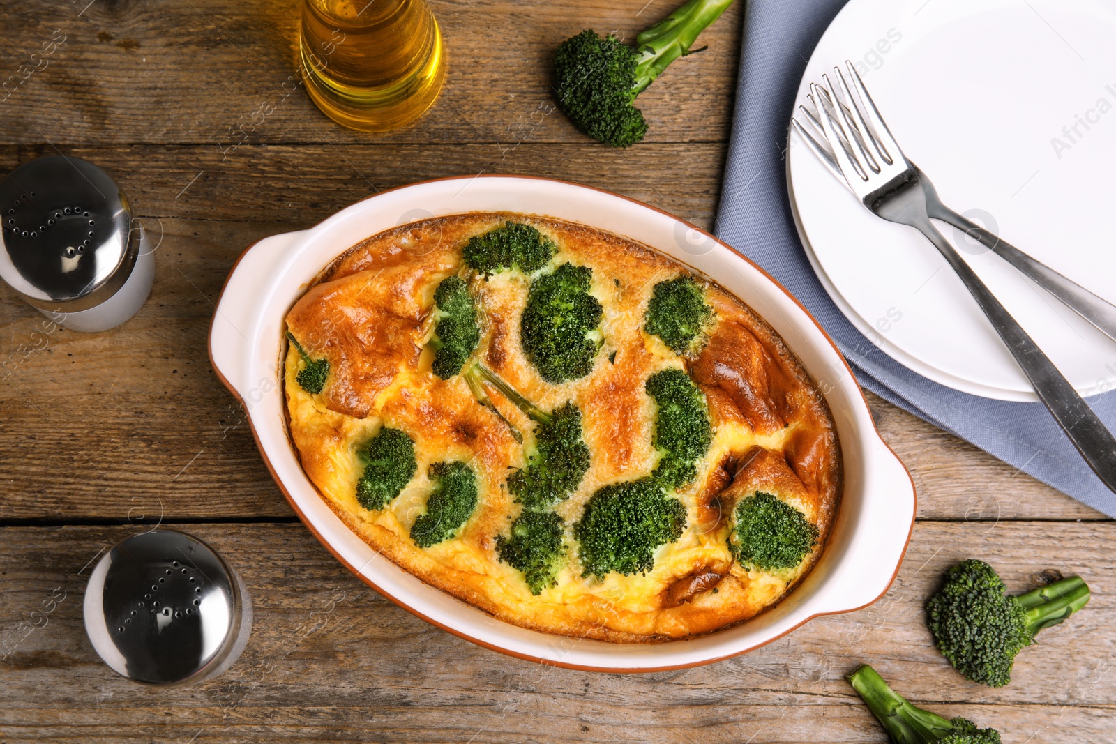 Photo of Tasty broccoli casserole in baking dish on wooden table, flat lay