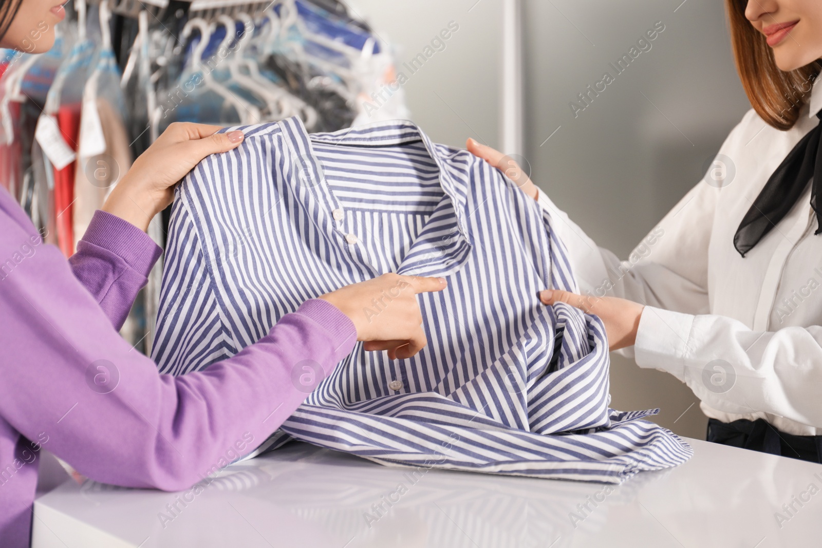 Photo of Client showing blouse to worker at dry-cleaner's, closeup