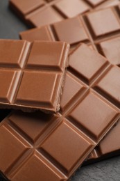 Photo of Delicious milk chocolate on black table, closeup