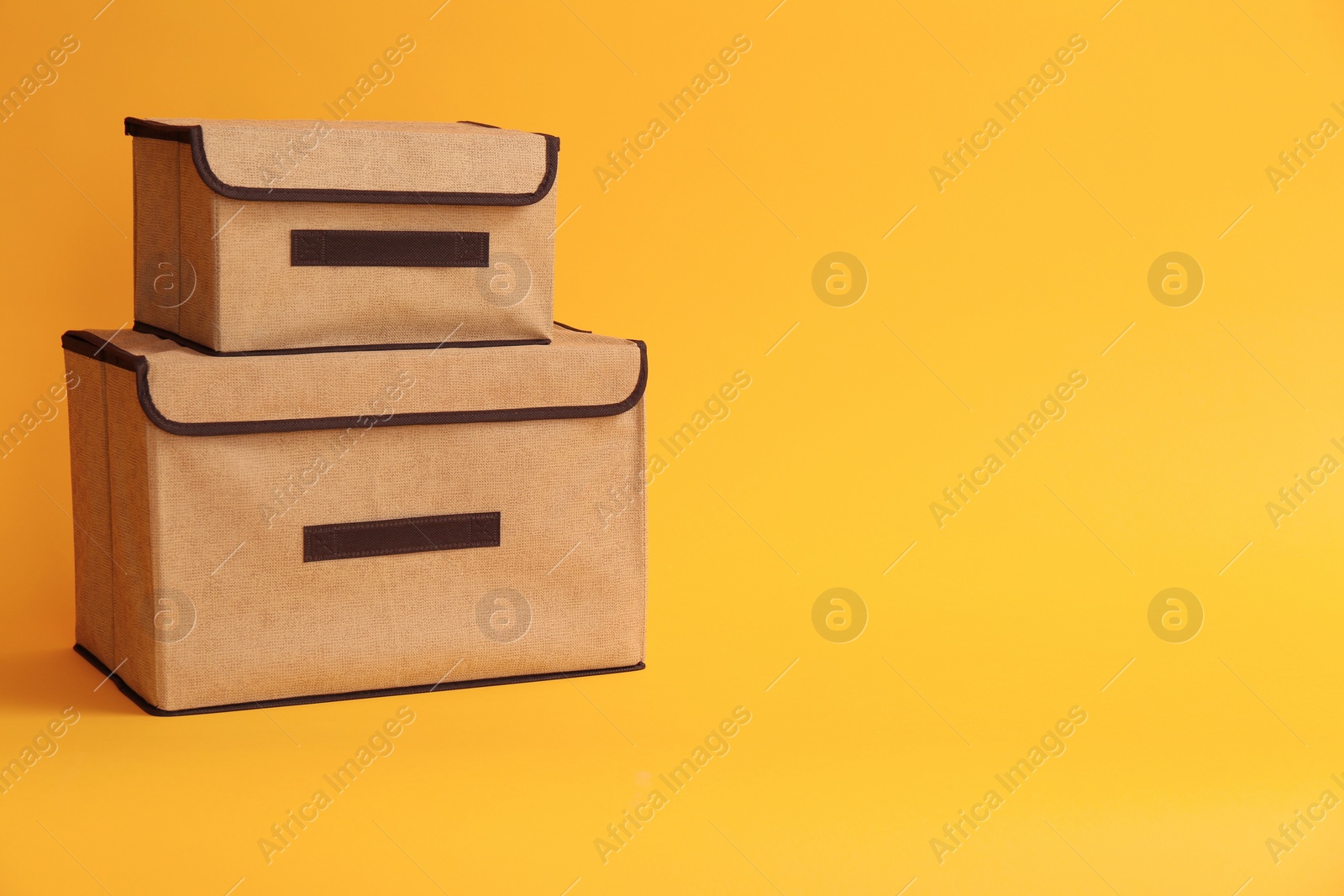 Photo of Two textile storage cases on yellow background. Space for text