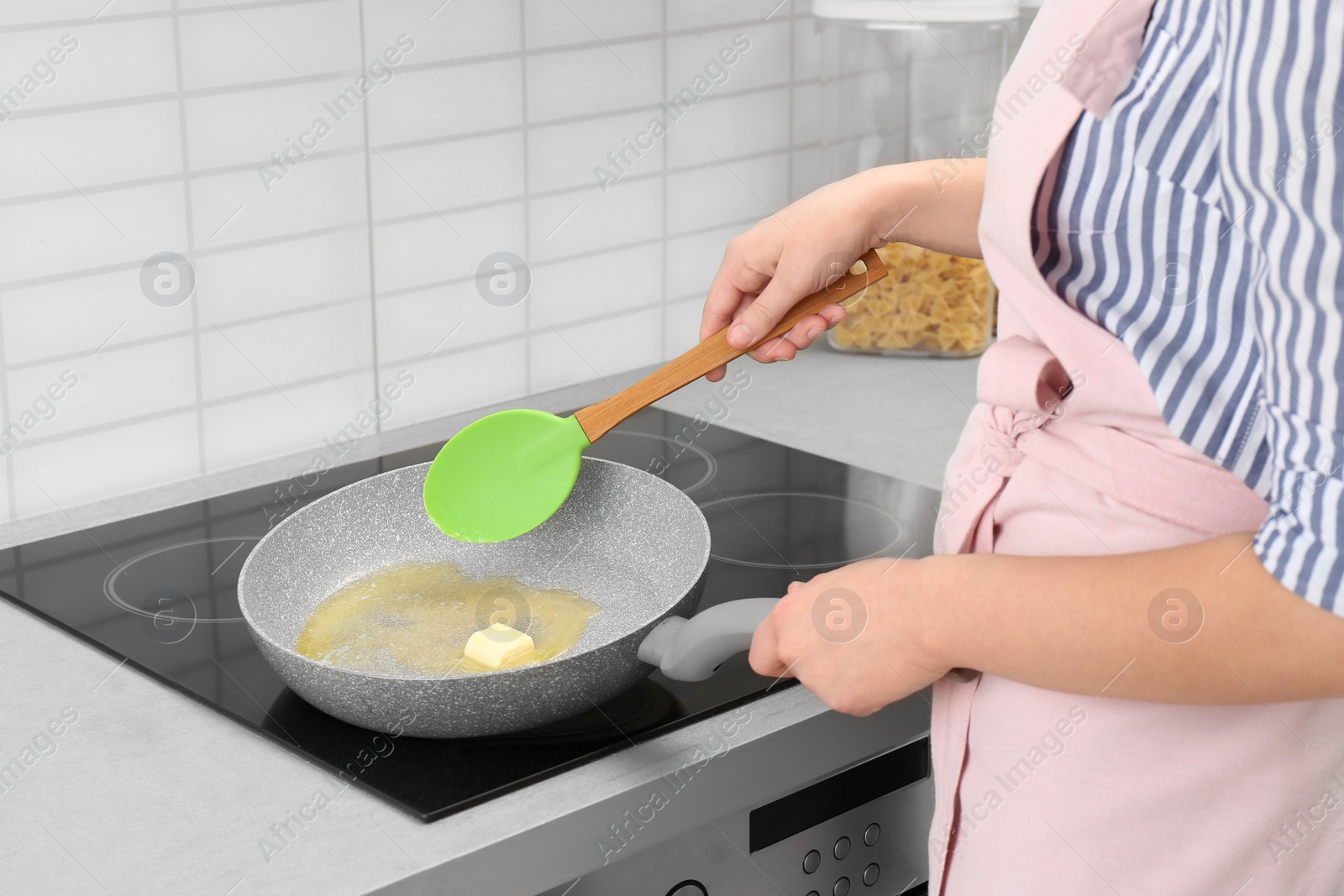 Photo of Woman stirring butter in frying pan on electric stove, closeup