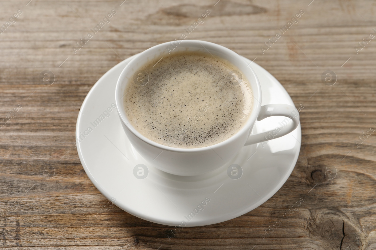 Photo of Tasty coffee in cup on wooden table, closeup