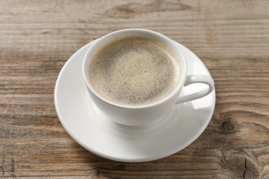 Photo of Tasty coffee in cup on wooden table, closeup