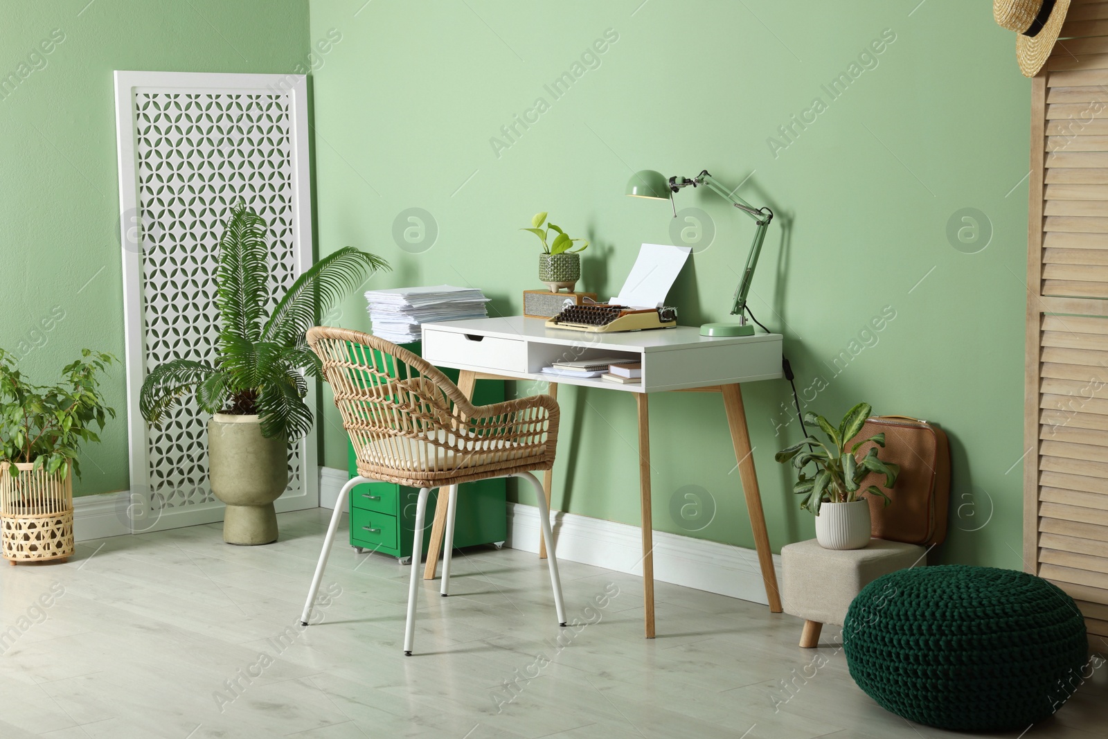 Photo of Writer's workplace with typewriter on wooden desk near pale green wall in room