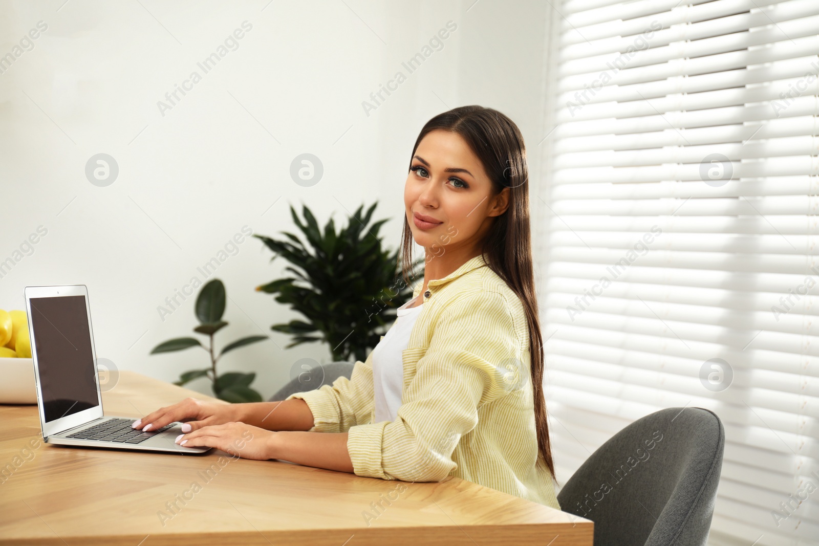 Photo of Young woman working with laptop in office