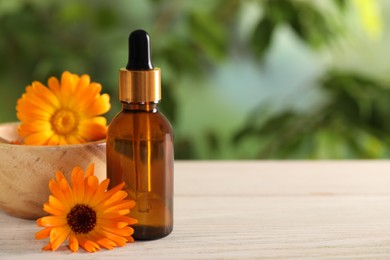 Bottle of essential oil and beautiful calendula flowers on white wooden table outdoors, closeup .Space for text