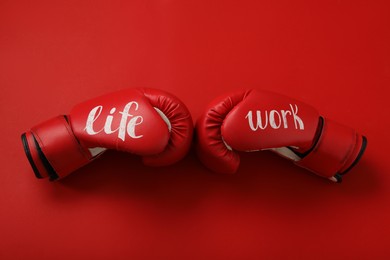 Boxing gloves with words Work and Life on red background, flat lay. Balance concept
