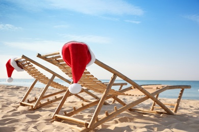 Sun loungers with Santa's hats on beach. Christmas vacation