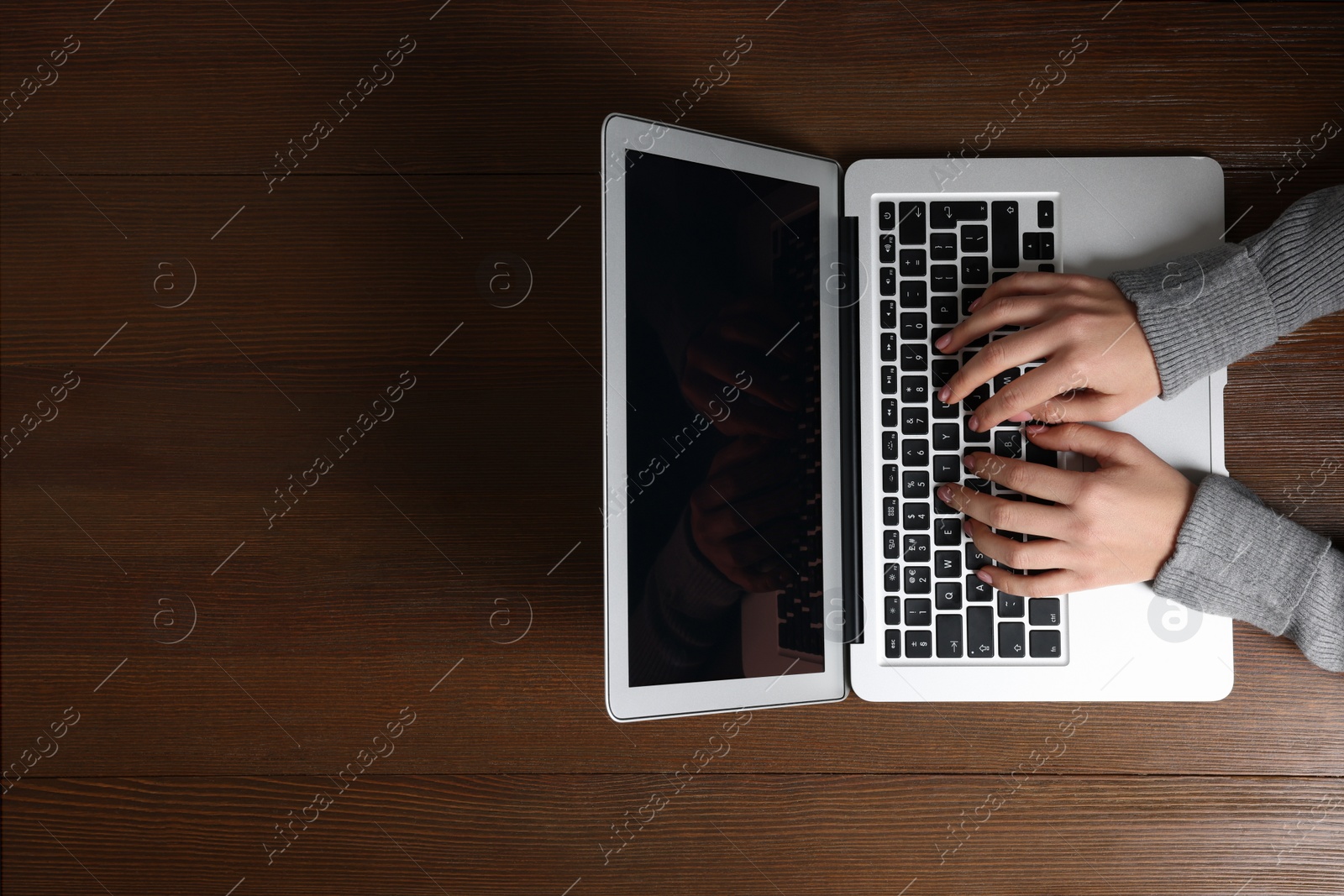Photo of Woman working with laptop at wooden table, top view. Space for text