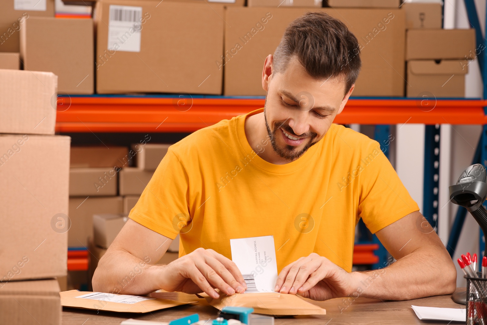 Photo of Post office worker sticking barcode on parcel at counter indoors