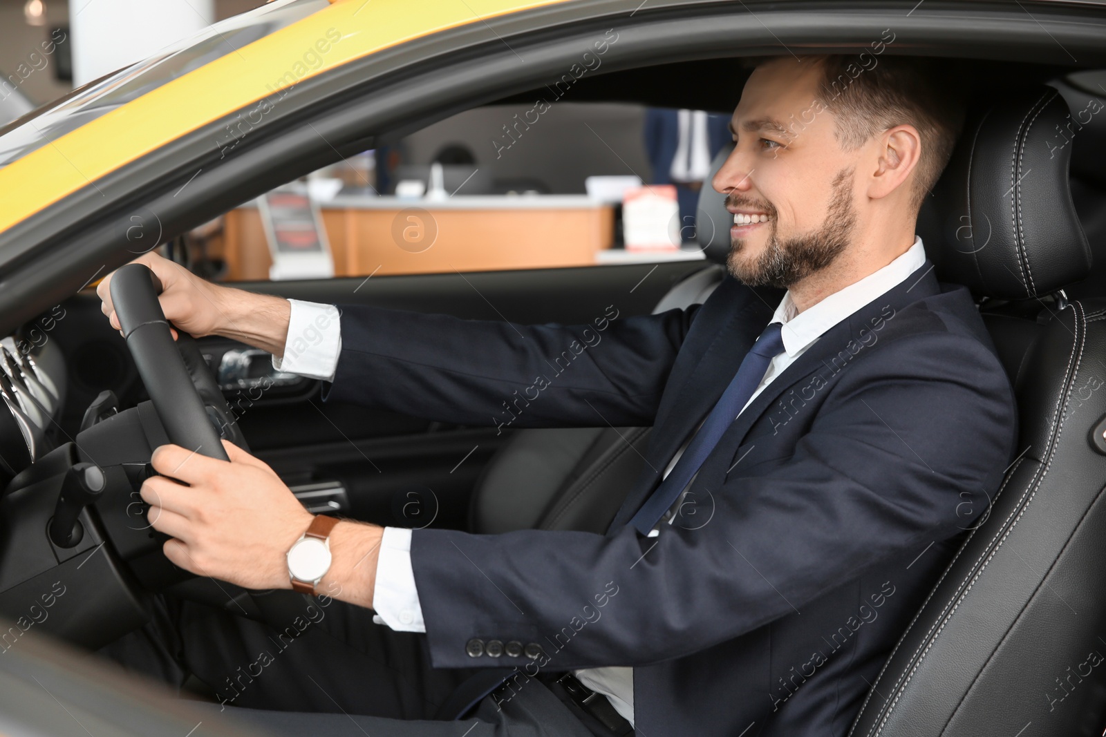 Photo of Young businessman sitting in driver's seat of auto. Buying new car